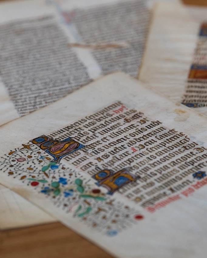 three colorful pages from medieval manuscripts, scattered on a table